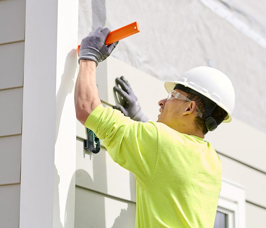 A woman in workwear inspecting some siding.
